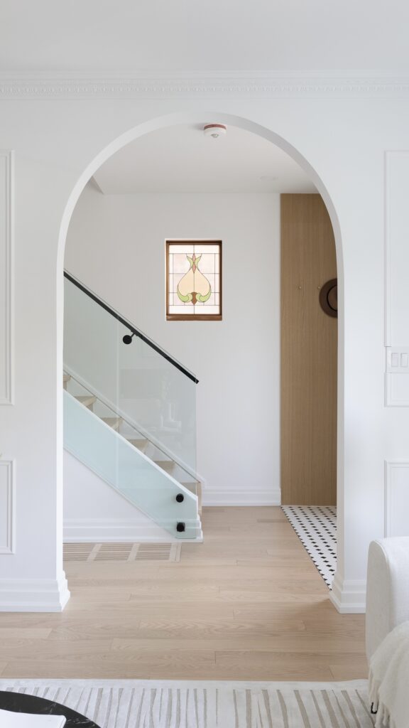 A modern, elegant interior featuring white plaster crown moulding, arched entryways, and contemporary furnishings.
