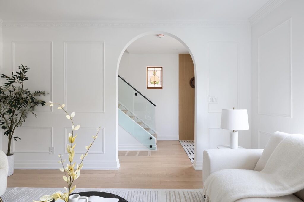 A modern, elegant interior featuring white plaster crown moulding, arched entryways, and contemporary furnishings.
